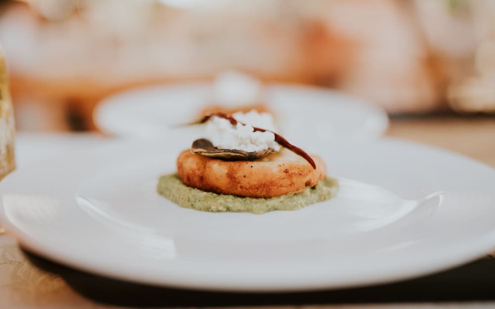 Piatto gourmet con cuori di carciofo, crema e nocciole su piatto bianco
