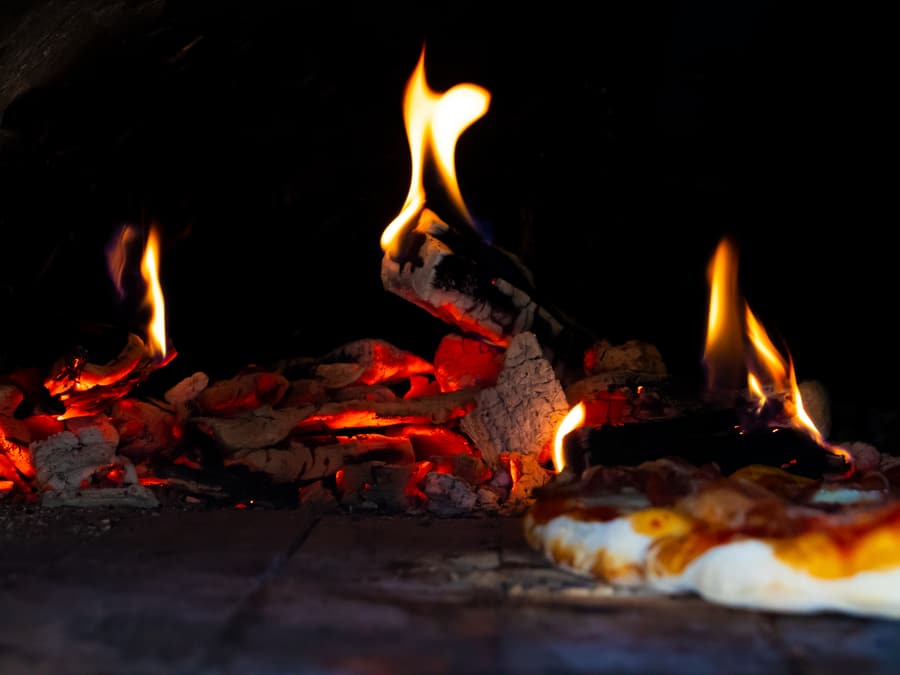 La bocca del forno a legna con le fiamme sul fondo