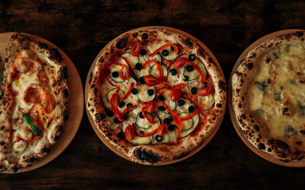 Pizza margherita napoletana con cornicione alto su un tavolo di legno scuro