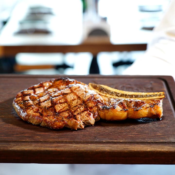 Bistecca alla fiorentina su un tagliere di legno con rosmarino