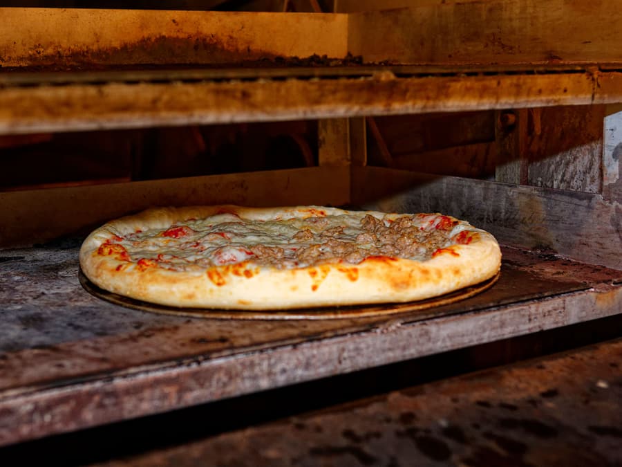 La bocca del forno con una pizza in cottura
