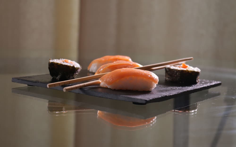 Quattro nigiri di pesce crudo disposti su una lastra di ardesia